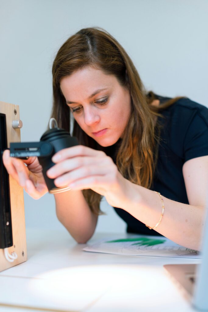 A focused female engineer tests a prototype light fixture in a modern office setting, highlighting engineering and design work.
