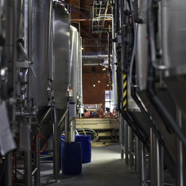 Inside view of a modern brewery with large stainless steel tanks and machinery for beer production.